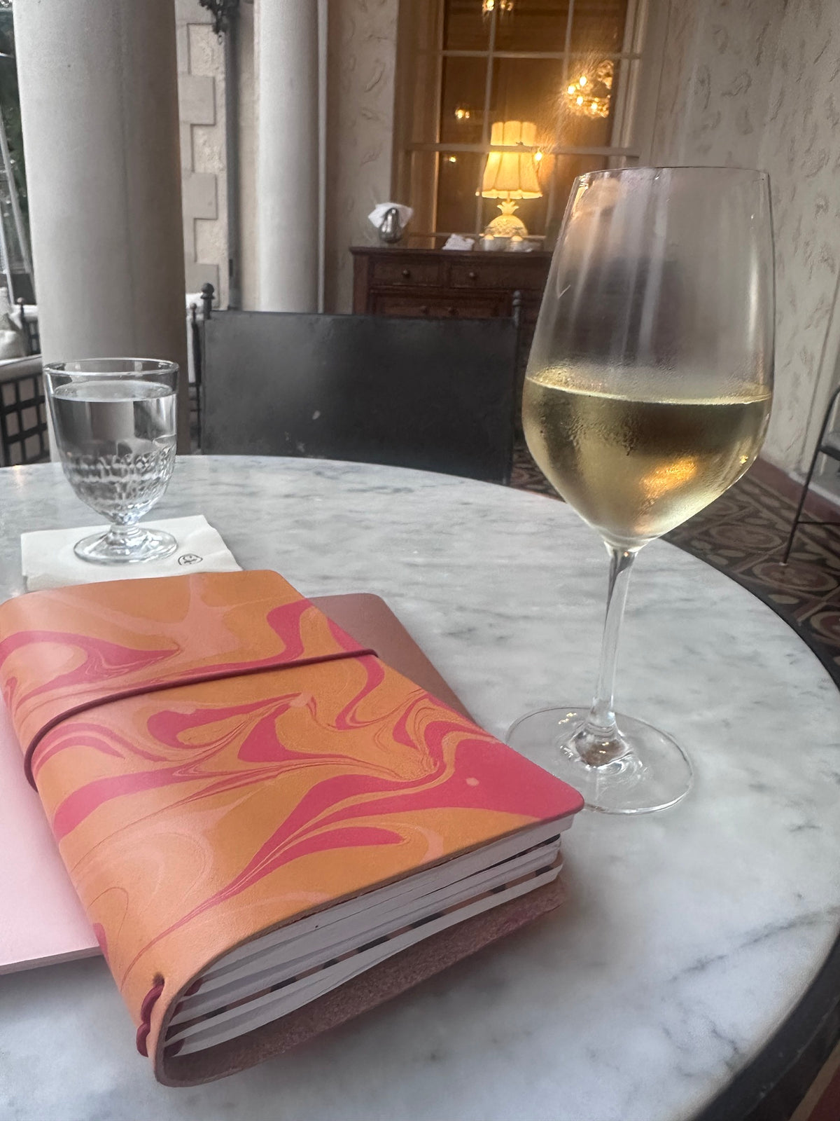 Marbled leather folio wrapped around Classic Notebooks on a marble café table